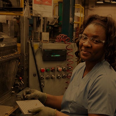 employee standing next to factory machines